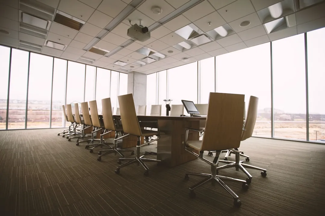 An empty modern conference room with rolling chairs around a long table and floor-to-ceiling windows