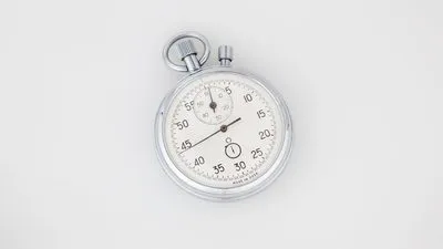 A silver mechanical stopwatch lying on a plain white surface
