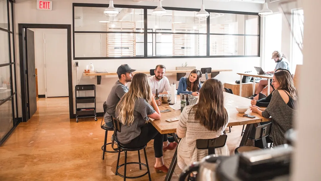 A group of coworkers sitting around a table eating and talking in an open office