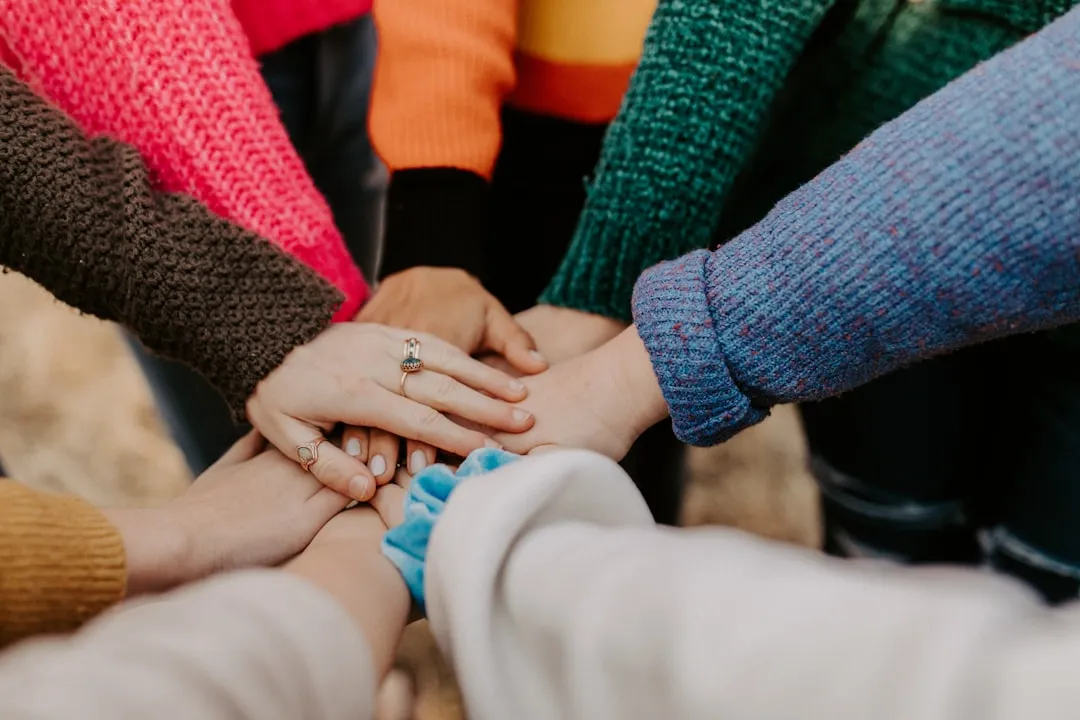 Close-up of a group of people's hands stacked together in a huddle
