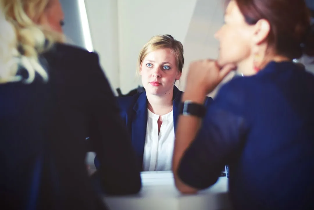 A woman listening attentively to two colleagues in the foreground during a conversation